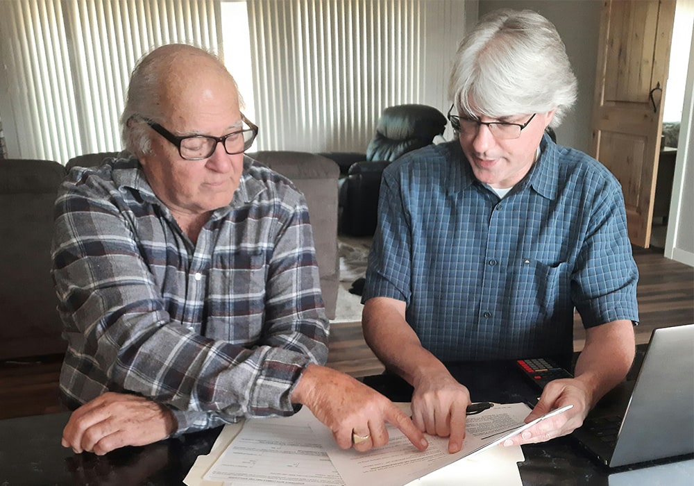 Rich sitting with an elderly gentleman reviewing his documents during the consultation.